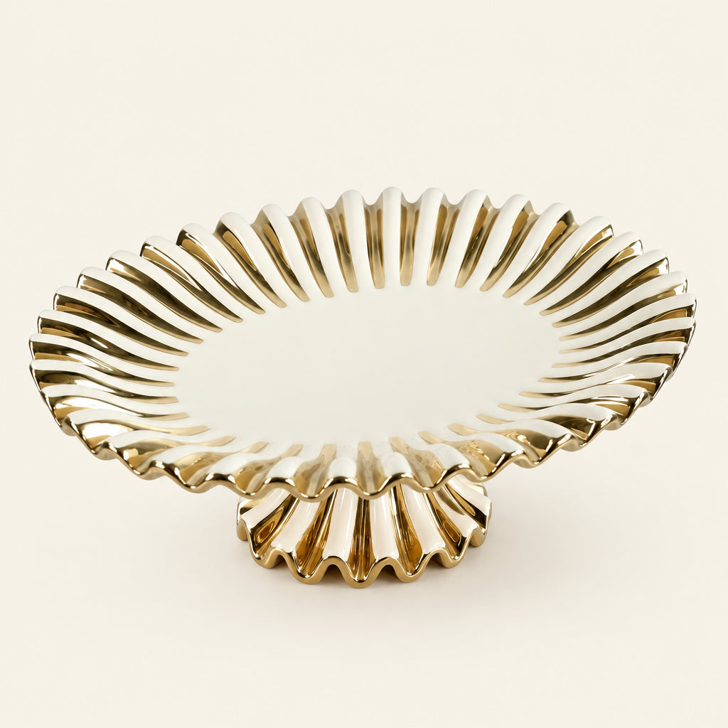 Gold Ray 15-inch oval pedestal cake stand with a fluted, scalloped gold rim, on marble