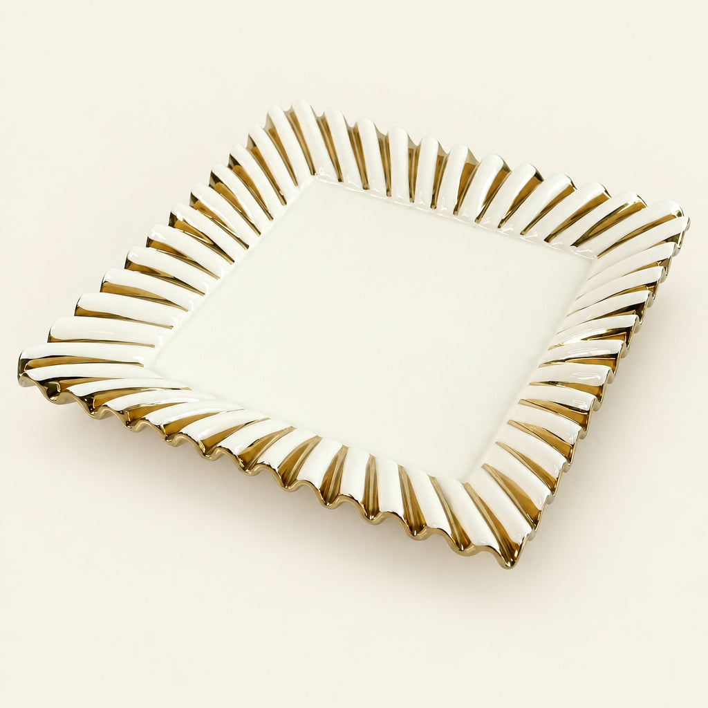 Gold Ray 12-inch square white porcelain serving tray with a fluted gold sunburst rim, on grey marble