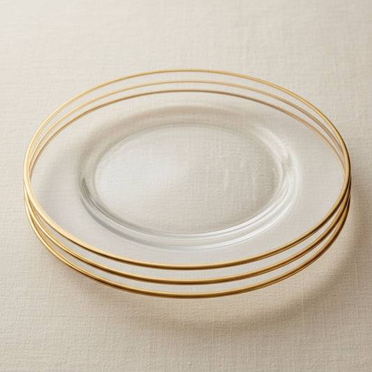 A collage of clear glass plates with a thin gold rim, shown in close-up and styled on a table setting with white plates, gold cutlery, and a cream tablecloth.